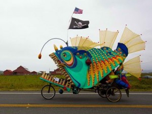 An art bike of a green, blue, and oranage monster fish complete with pirate flag and teeth.